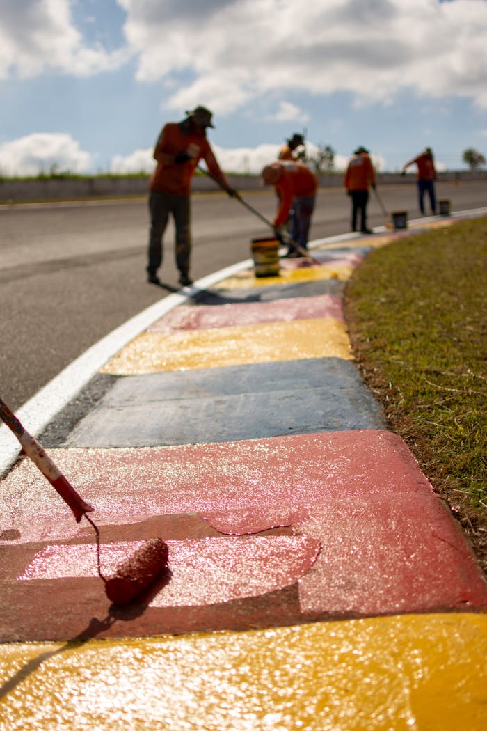Team painting vibrant colors on a racing track curve in Londrina, Brazil.